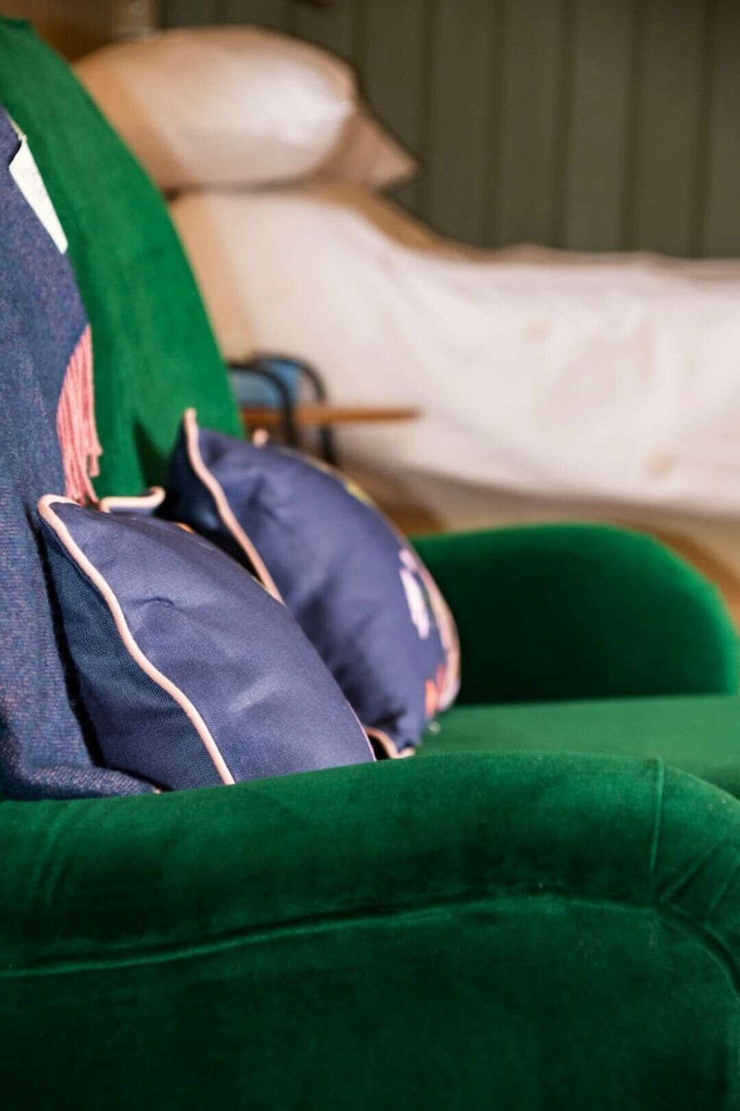 Un canapé vert avec deux coussins, une couverture et un coussin à motifs rouges et blancs.