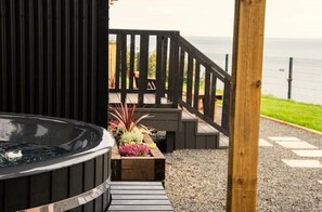 Een jacuzzi, een houten terras en uitzicht op de oceaan.