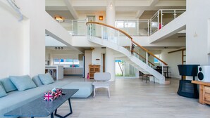 A spacious living area with a curved staircase, a sofa, a coffee table, and a dining area. - White House (Liuqiu)