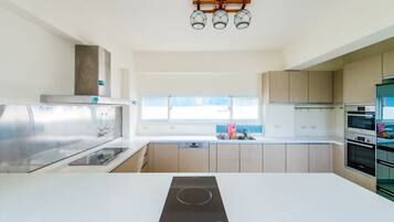 Una cocina moderna con una isla central, electrodomésticos de acero inoxidable y un ventanal que proporciona luz natural.