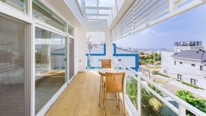 A balcony with a wooden floor, a table, and two chairs. - White House (Liuqiu)