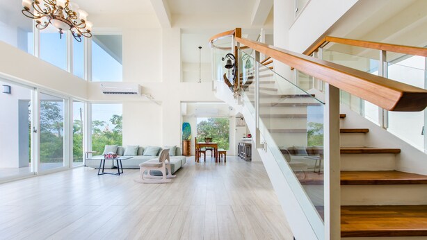A spacious living area with a wooden staircase, large windows, and a modern chandelier. - White House (Liuqiu)