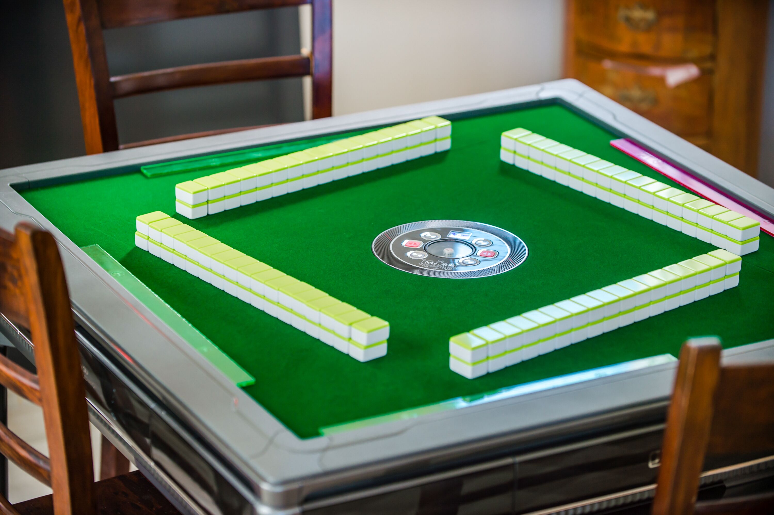 A pool table with green felt, surrounded by wooden chairs.