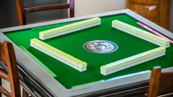 A pool table with green felt, surrounded by wooden chairs.