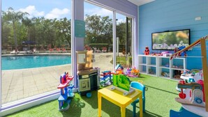 Un espace de jeux pour enfants avec des jouets et une vue sur la piscine.