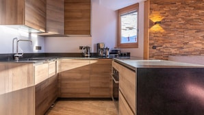 Une cuisine moderne avec des meubles en bois, un îlot central intégré, une lucarne et une fenêtre donnant sur un paysage enneigé.