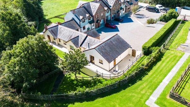 A large, multi-story building with a courtyard, surrounded by lush greenery and a fenced perimeter. - Chy Pol (Wadebridge)