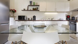 Eine moderne Küche mit einem Glastisch, weißen Schränken und Edelstahlgeräten.