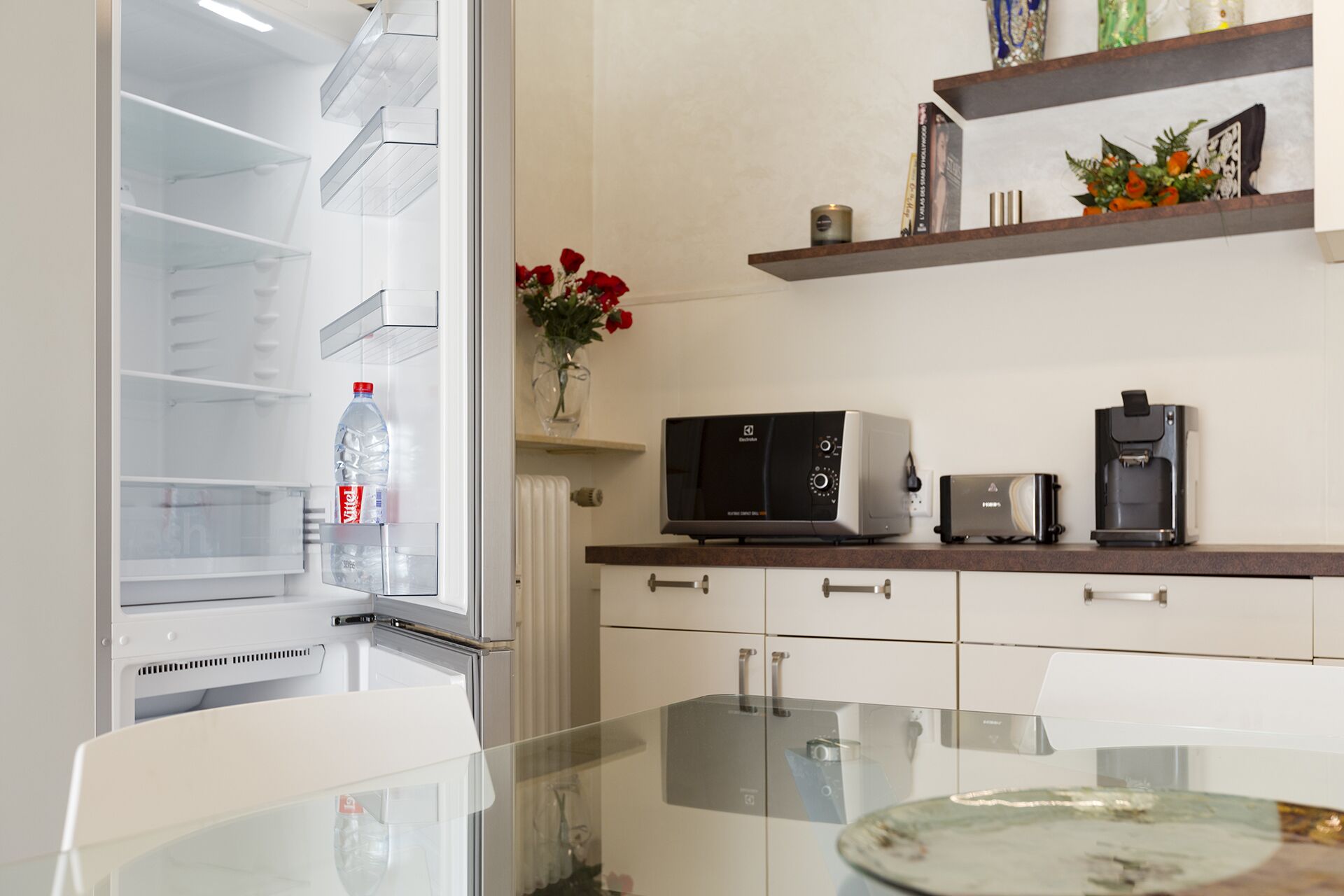 A modern kitchen with a refrigerator, microwave, toaster, and coffee maker on the countertop.