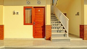 Ein Gebäudeeingang mit einer Holztür, die mit der Nummer 4 gekennzeichnet ist, einer Treppe mit weißen Geländern und einem Fliesenboden.
