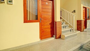 Ein Gebäudeeingang mit Holztür, Treppe und Fliesenboden.