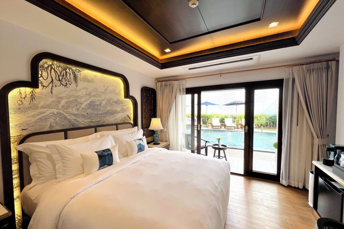 Ein geräumiges Schlafzimmer mit einem großen Bett, Blick auf einen Pool und einem Balkon.