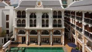 Un hotel de varios pisos con un patio central, balcones y una piscina.