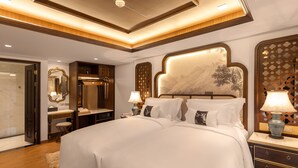 Una habitación de hotel moderna con una cama grande, una tocador con espejo, un escritorio y una mesita de noche con lámparas.