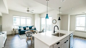 A modern kitchen with a white island, a built-in sink, and a ceiling fan.