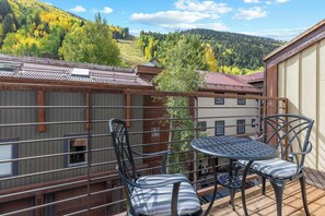 A balcony with a table and chairs, overlooking a forested hillside. - Awesome Views; Ski In/Out & lift is 100 steps from the Door (Telluride)
