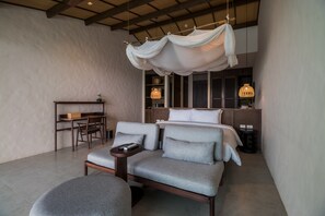 Un dormitorio moderno con cama, sofá, escritorio y dosel colgante.
