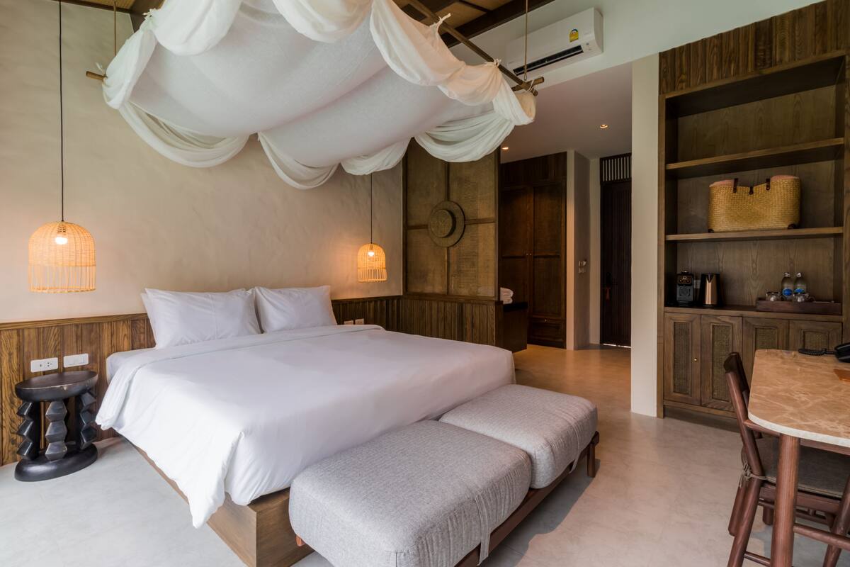 A bedroom with a large bed, bedside tables, a hanging canopy, and a wooden wardrobe.