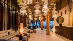 A spacious lobby with a modern design, featuring a reception desk, comfortable seating areas, and unique hanging light fixtures. - The Flow Samui Beach Resort (Koh Samui)