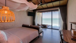 A bedroom with a large bed, a wooden table, a TV mounted on the wall, and a view of the ocean through large windows. - The Flow Samui Beach Resort (Koh Samui)