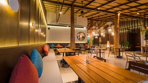 A restaurant with wooden tables and benches, a high ceiling with exposed beams, and pendant lighting. - The Flow Samui Beach Resort (Koh Samui)