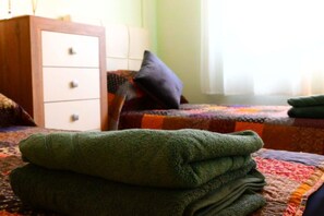 Una habitación con una cama, un aparador de madera y una pila de toallas dobladas.