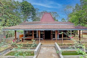 Ein traditionelles Gebäude mit einem Ziegeldach, einer Veranda und einem Garten mit Wasserspielen.