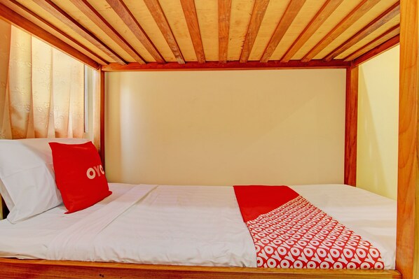 Una cama individual con ropa de cama blanca y una colcha de diseño rojo y blanco.
