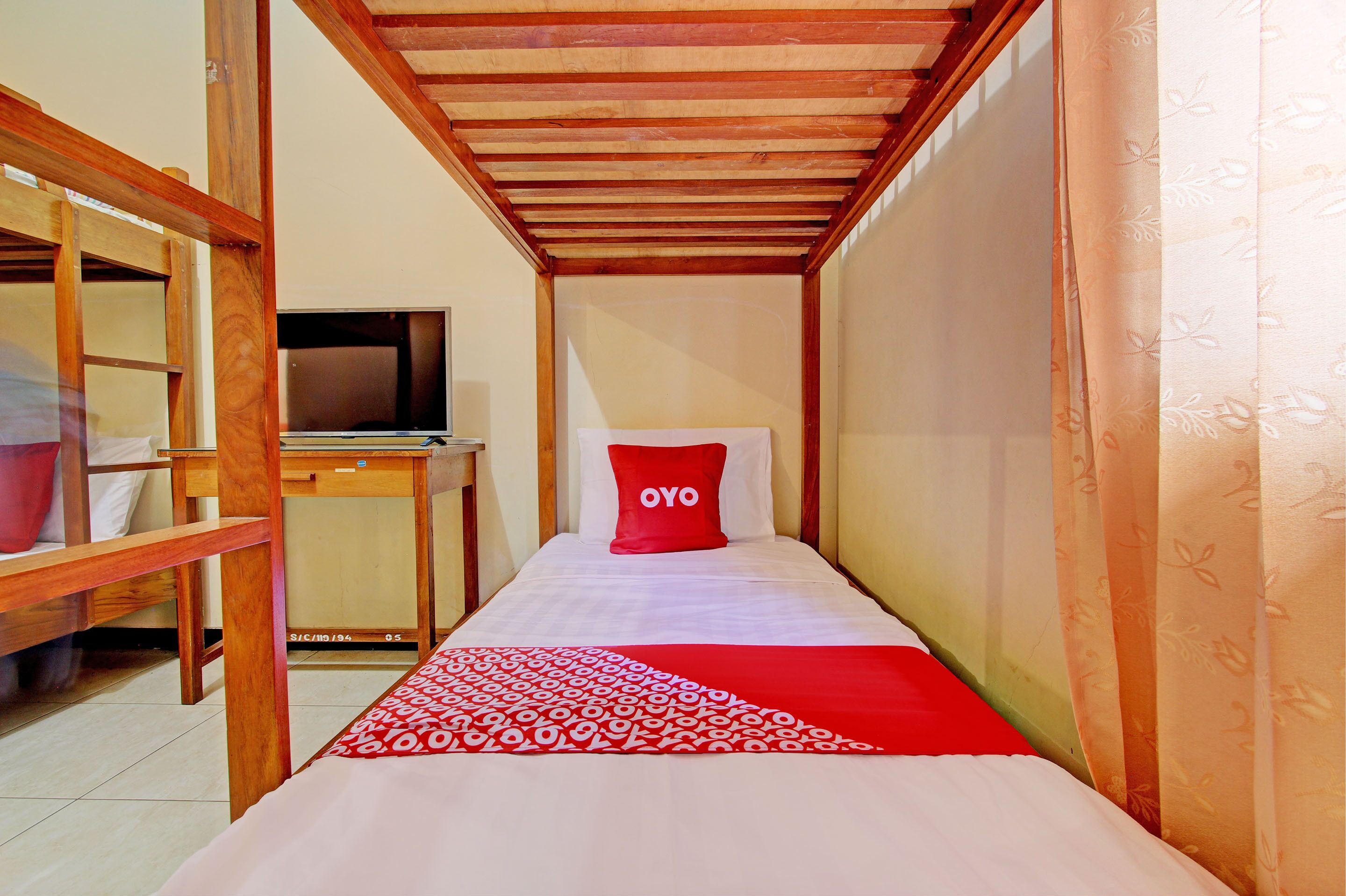 Une petite pièce comprenant un lit, un bureau en bois et un téléviseur.