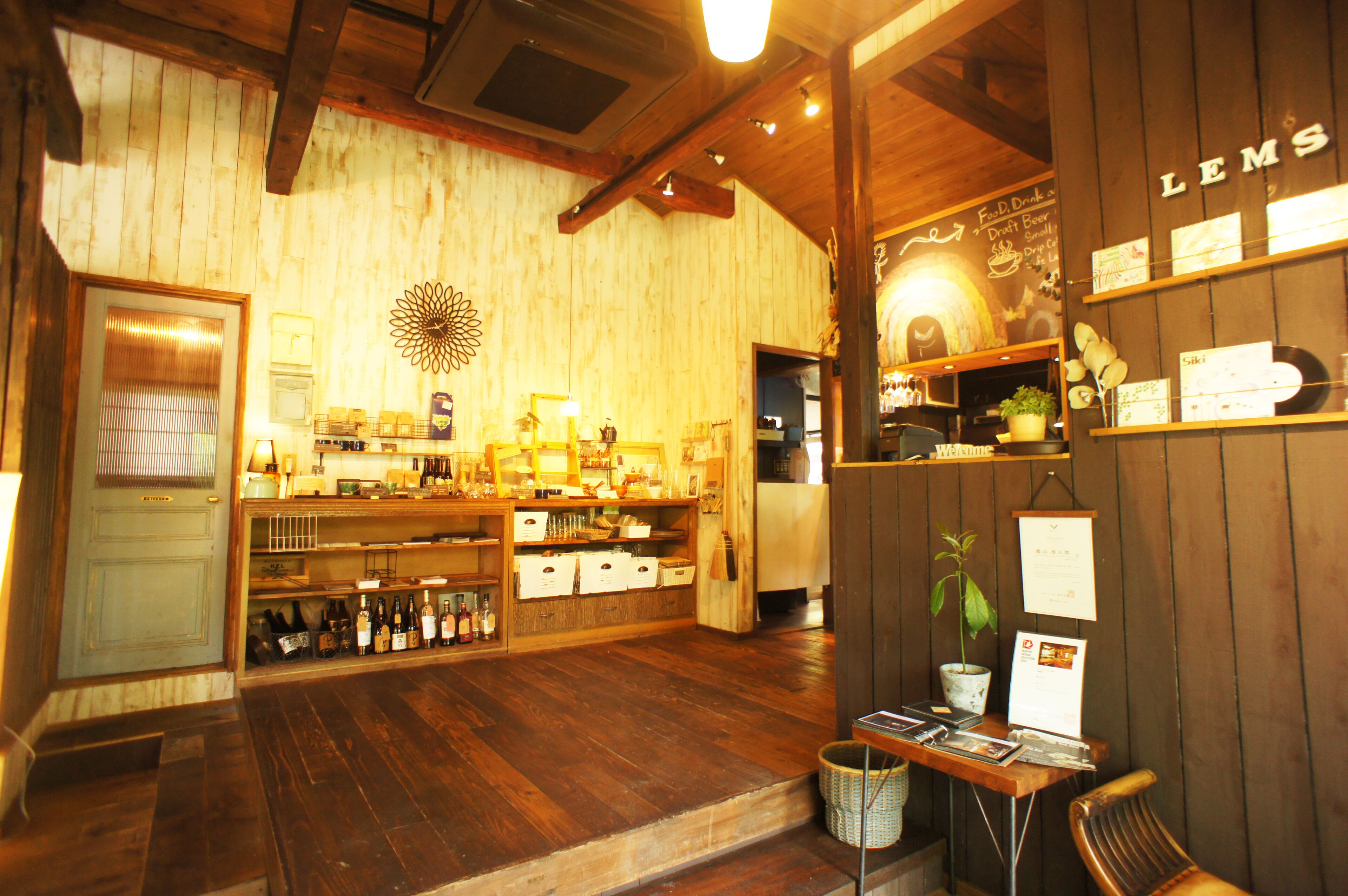 A cozy bar with wooden walls and shelves displaying various bottles and a chalkboard menu.