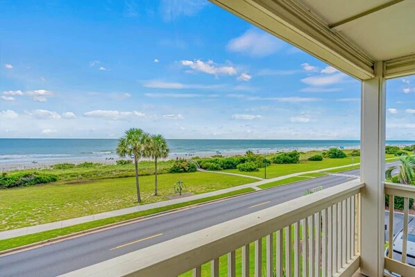 A balcony with a view of the beach and ocean.
