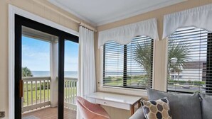 A room with a balcony, a desk, a chair, and a sofa. - Ocean Forest Villas Unit E210 - Oceanfront (Myrtle Beach)