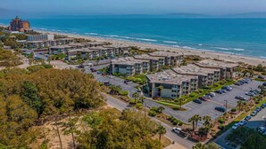 A coastal residential area with apartment buildings, a parking lot, and a beach. - Ocean Forest Villas Unit E210 - Oceanfront (Myrtle Beach)