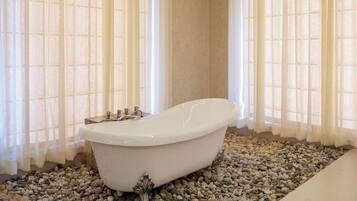 A bathroom with a freestanding bathtub, white curtains, and an air conditioning unit.