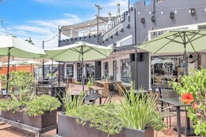 Un espace extérieur aménagé avec des tables, des chaises, des parasols et des plantes en pot.
