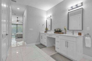 A modern bathroom with a large mirror, vanity, and a ceiling fan. - Modern Escape - Pet Friendly,  Salt Pool, 6 Cart ERV (Cape Coral)