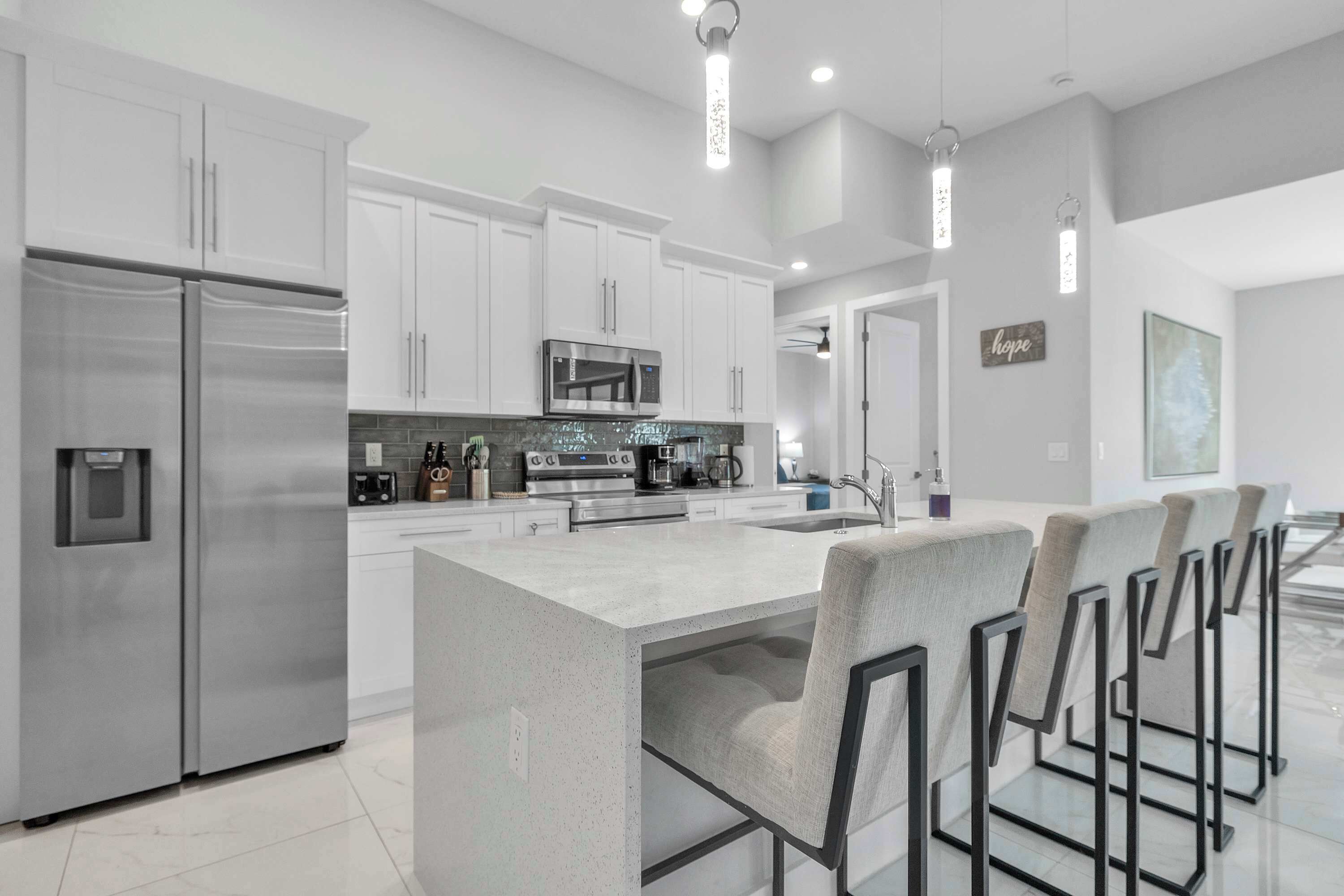 A modern kitchen with stainless steel appliances, a central island, and bar-style seating.