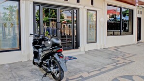 A motorcycle parked in front of a building with large windows and a tiled floor. - Hotel O Guest House Nusa Indah Syariah (Bandar Lampung)