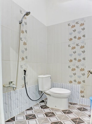 A bathroom with a toilet, a shower, and a toilet paper holder. - Hotel O Guest House Nusa Indah Syariah (Bandar Lampung)