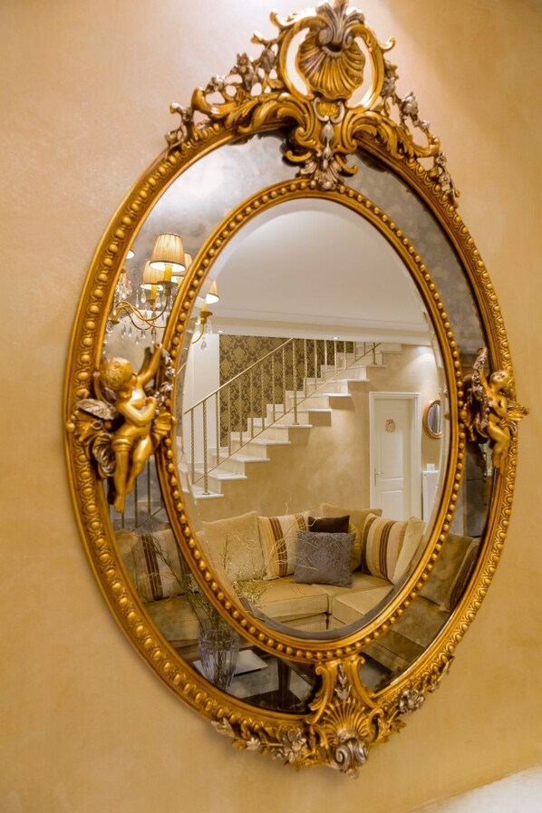 Reflecting classic style, this room features a staircase, plush sofa, and ornate mirror.