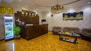 A reception area with a wooden desk, a clock, a chandelier, and a wall-mounted display. - Samarkand (Samarkand)