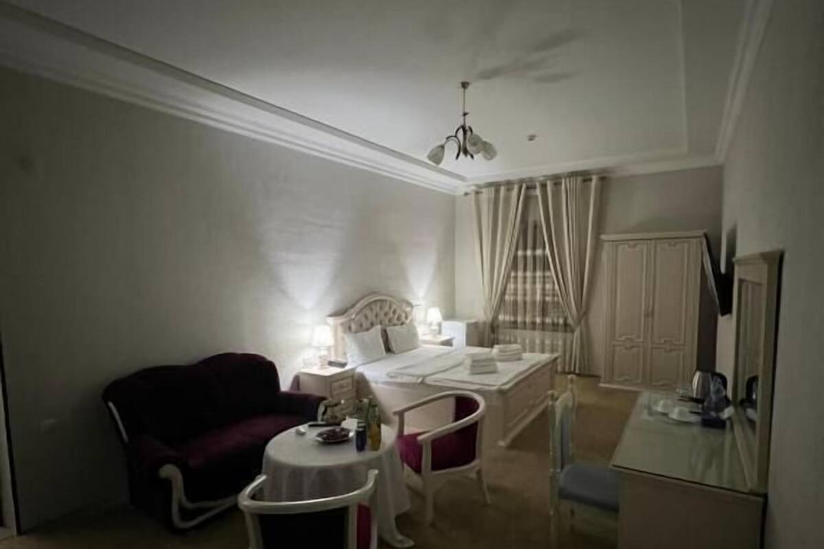 A compact bedroom with a bed, bedside table, and a small desk area.