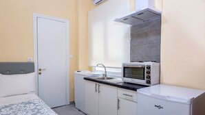 Una cocina pequeña equipada con microondas, lavamanos y refrigerador compacto.