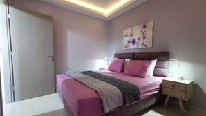 Ein Schlafzimmer mit einem Bett, Nachttischen, einer Deckenleuchte und einer Tür.