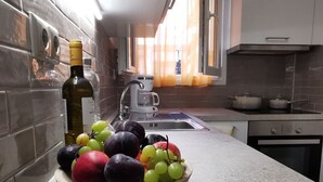 Eine Küche mit Obstschale auf der Arbeitsfläche, einer Kaffeemaschine und einem Fenster mit Vorhängen.
