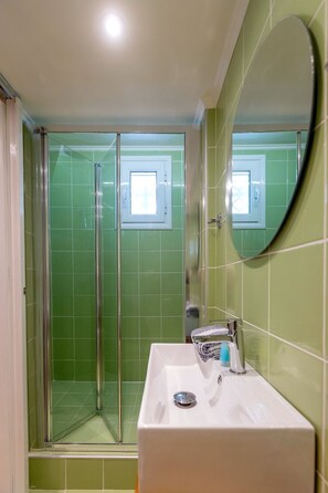 A bathroom with a shower, a sink, and a mirror.