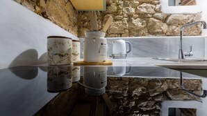Una cucina con parete in pietra, un lavello e un piano di lavoro con una macchina da caffè e due tazze.