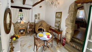 A rustic dining area with a stone fireplace, wooden furniture, and a chandelier. - The Old Oven House - The apartment was renovated to strict traditional standards. (Corfu)