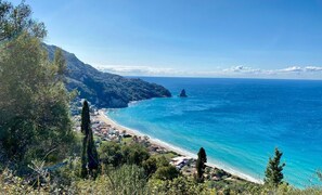 A coastal landscape with a clear view of the sea, a beach, and a mountainous backdrop. - The Old Oven House - The apartment was renovated to strict traditional standards. (Corfu)