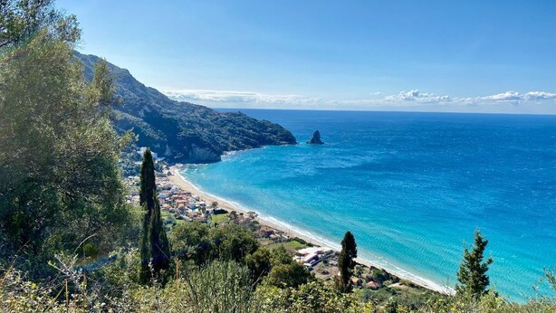 A coastal landscape with a clear view of the sea, a beach, and a mountainous backdrop. - The Little Patio House (Corfu)